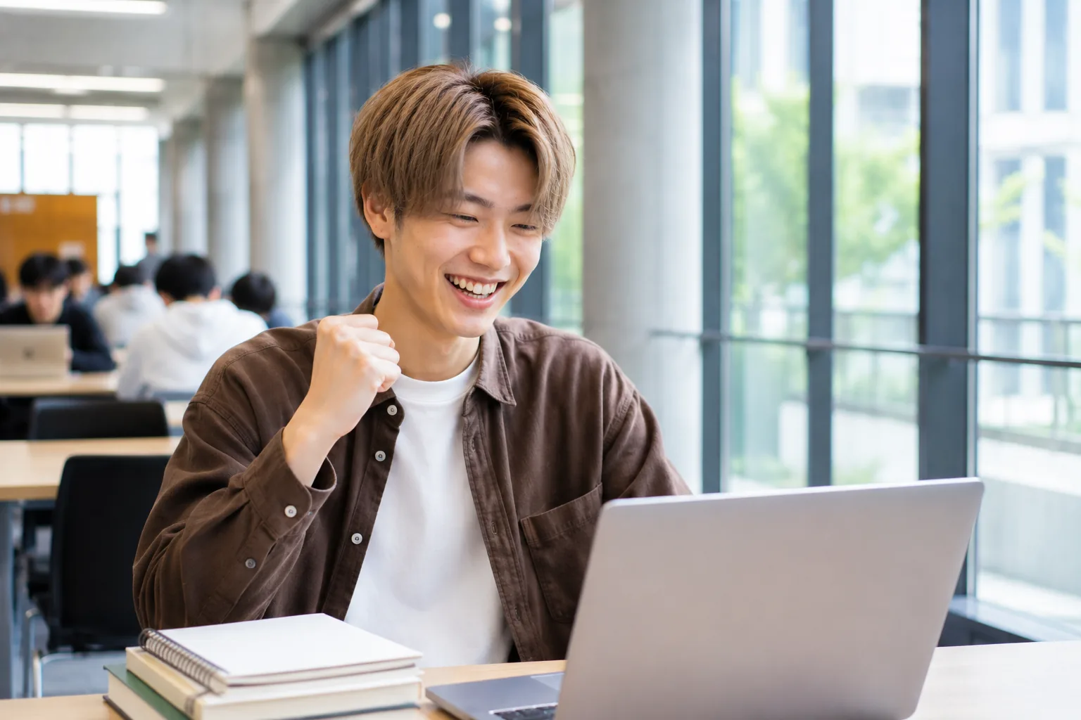 ノートパソコンに向かいガッツポーズする大学1年生のHさん