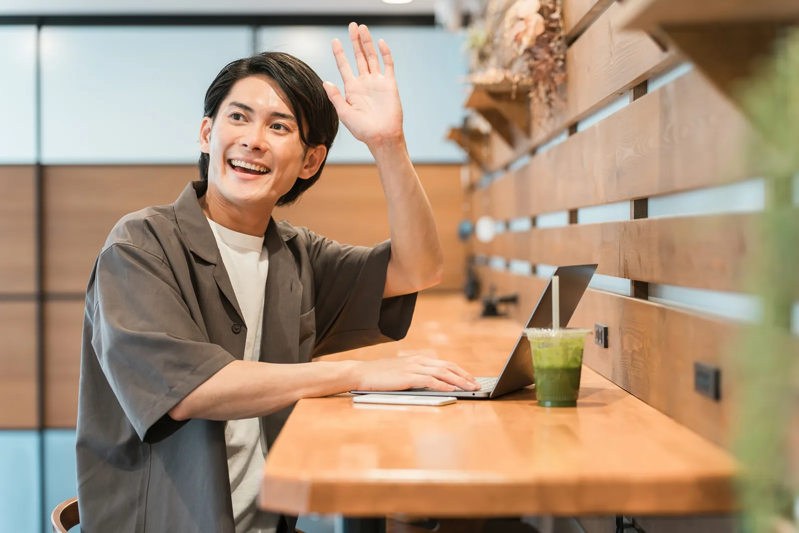 カフェでノートパソコンを開き楽しそうに働く男性