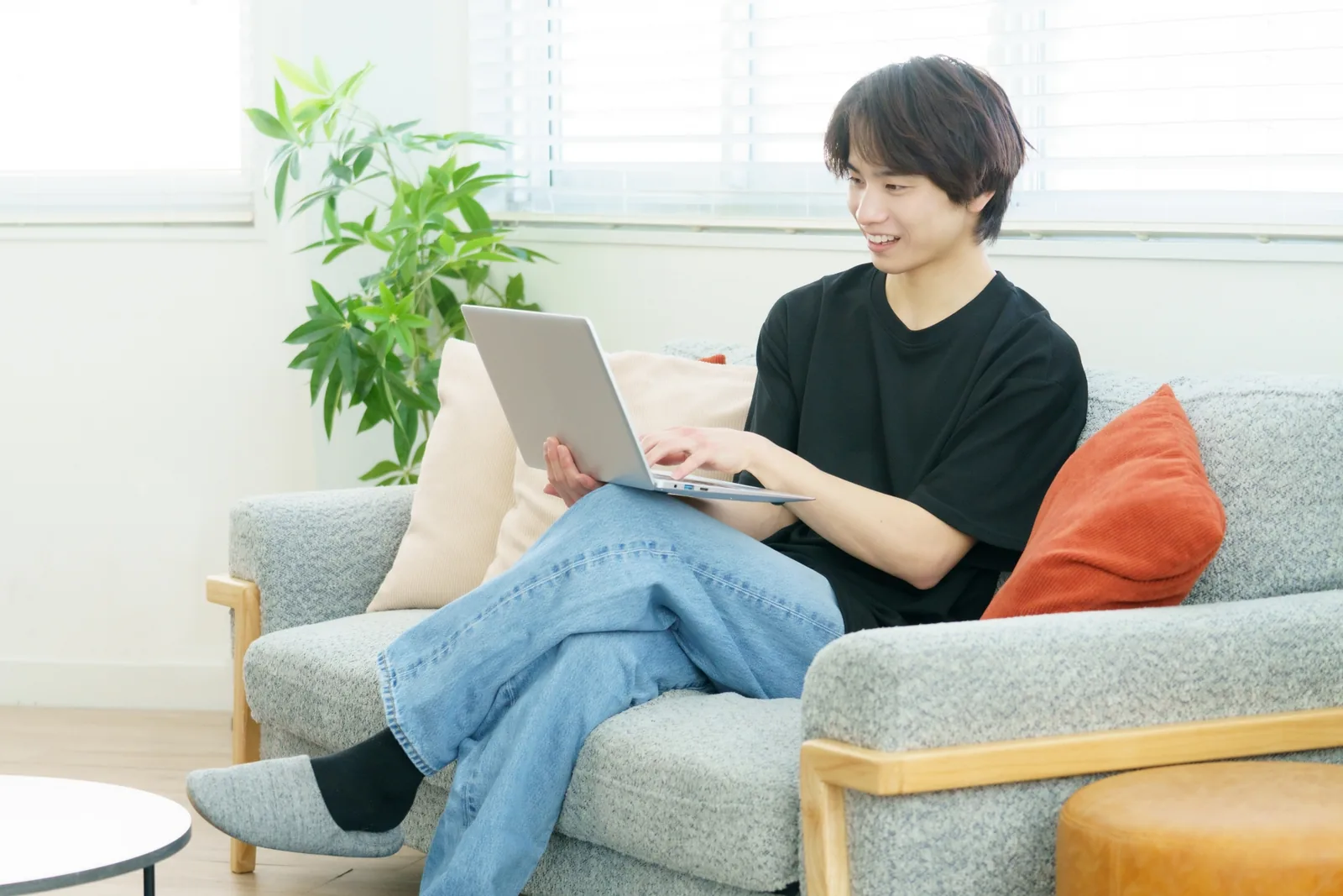自宅のソファでノートパソコンを使い学ぶ男性